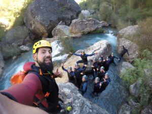 Selfi del guía con un gran grupo dentro del barranco del Ventano del Diablo al lado de una gran cascada de agua